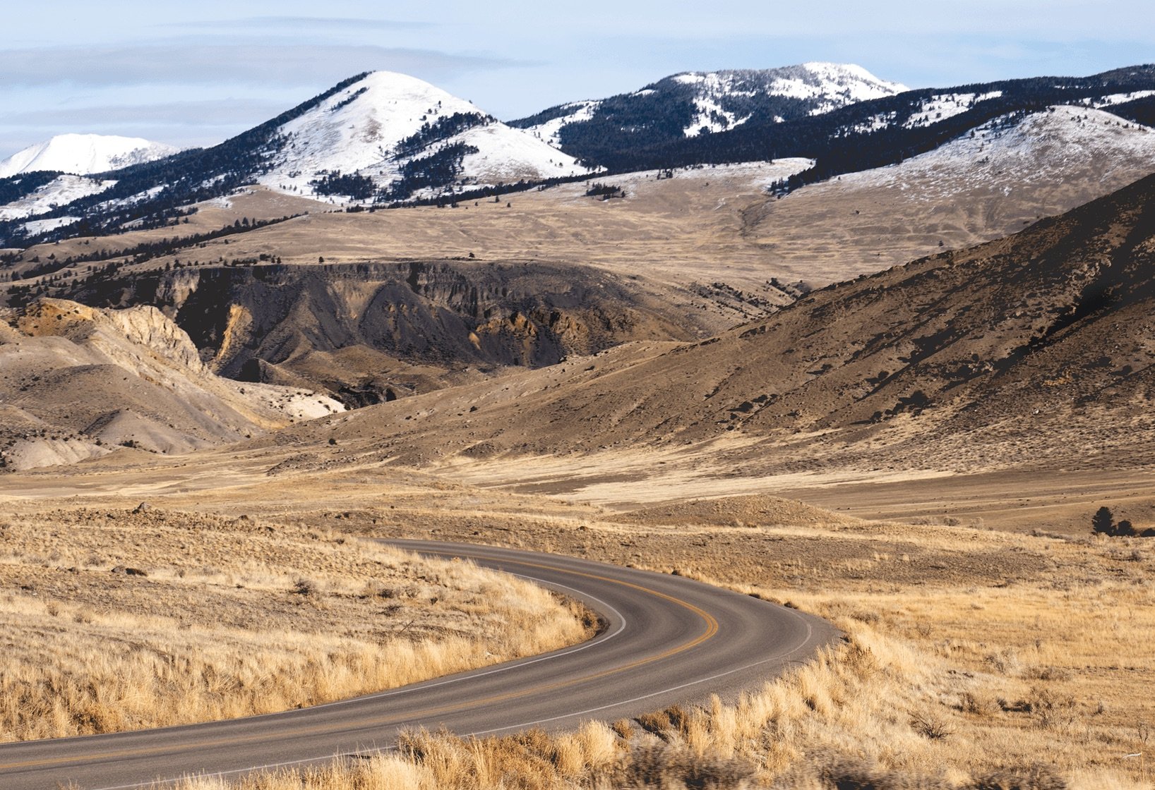 a winding road with snow-capped mountains in the background